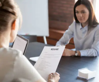 Two women sitting at a table with a resume